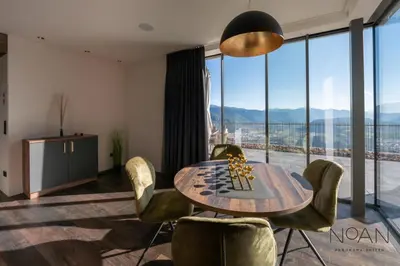 a dining room with a table and chairs and a large window at NoAN Panorama Suiten - D i c k e n s in San Genesio Atesino