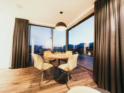 a dining room with a table and chairs and a large window at NoAN Panorama Suiten - D i c k e n s in San Genesio Atesino