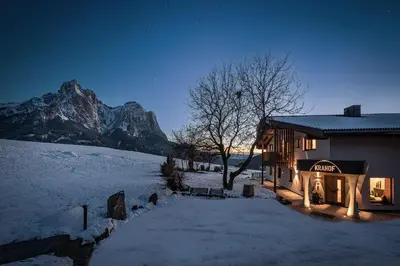 a house in the snow with a mountain in the background at Krahof Dolomites - Urlaub auf dem Bauernhof in Castelrotto