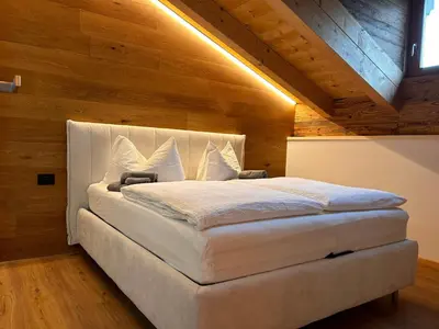 a large white bed in a room with wooden walls at Casa Franz in Tesero