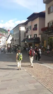 two people with backpacks walking down a city street at Appartements Tlusel in Ortisei