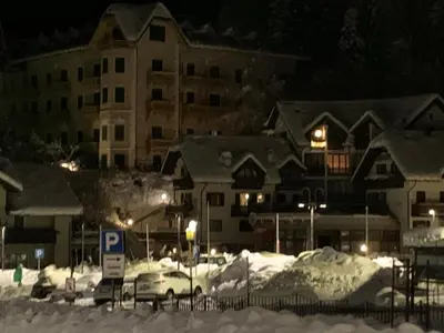a parking lot covered in snow at night at SISSI MENDEL Residence in Ronzone