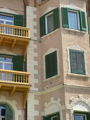 a building with green and white windows and balconies at SISSI MENDEL Residence in Ronzone