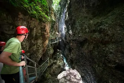 a man in a red helmet standing next to a waterfall at SISSI MENDEL Residence in Ronzone