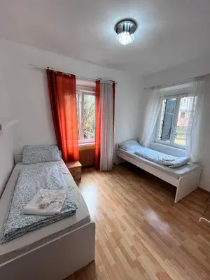 a bedroom with two beds and two windows at Druso Rooms in Bolzano