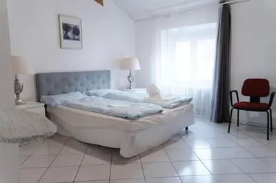 a bedroom with a large bed and a red chair at Druso Rooms in Bolzano