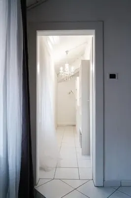 a hallway with a white door and a white tile floor at Druso Rooms in Bolzano