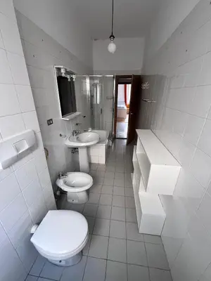 a white bathroom with two toilets and a sink at Druso Rooms in Bolzano