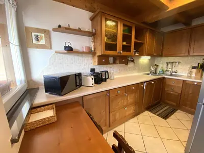 a kitchen with wooden cabinets and a table with a microwave at Casa LaLu in Cavalese