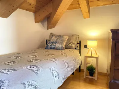 a bedroom with a bed and a lamp and wooden ceilings at Casa LaLu in Cavalese