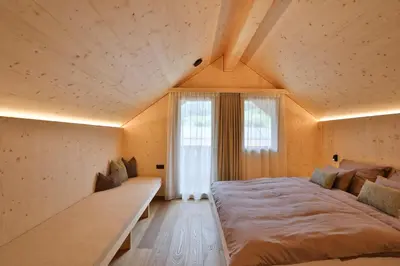 a bedroom with a large bed and a window at Mair am Graben Farm Chalets in Terento