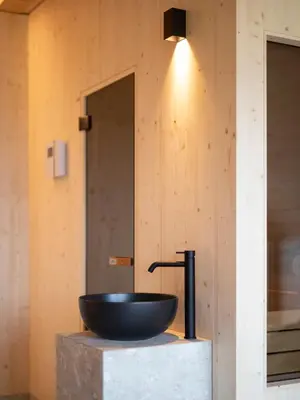 a bathroom with a bowl sink on a concrete block at Mair am Graben Farm Chalets in Terento
