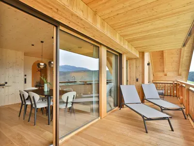 a dining room with glass doors and a table and chairs at Mair am Graben Farm Chalets in Terento