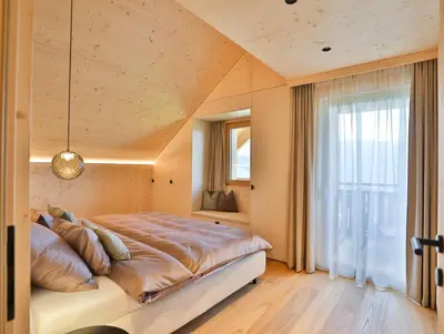 a bedroom with a large bed and a window at Mair am Graben Farm Chalets in Terento