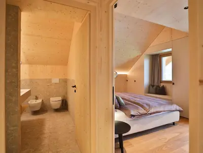 an attic bedroom with a bed and a bathroom at Mair am Graben Farm Chalets in Terento