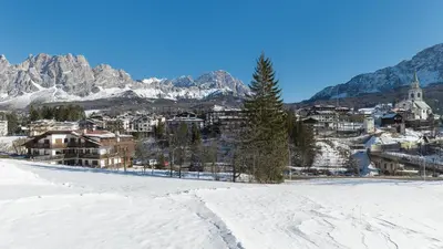 a town in the snow with mountains in the background at Villa Casanova - Stayincortina in Cortina dʼAmpezzo