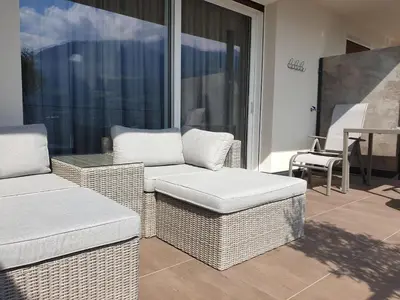 a patio with wicker chairs and a table on a balcony at Hotel Garni Herz in Tirolo