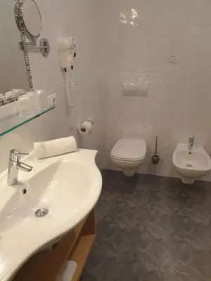 a white bathroom with a sink and a toilet at Hotel Garni Herz in Tirolo