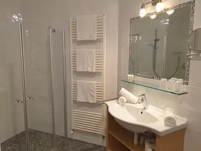 a white bathroom with a sink and a shower at Hotel Garni Herz in Tirolo