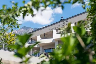 a hotel building with mountains in the background at Hotel Garni Herz in Tirolo
