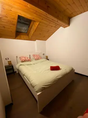 a bedroom with a large bed in a room with wooden ceilings at Romantica Mansarda Alpina-Ski & Natura in Tesero