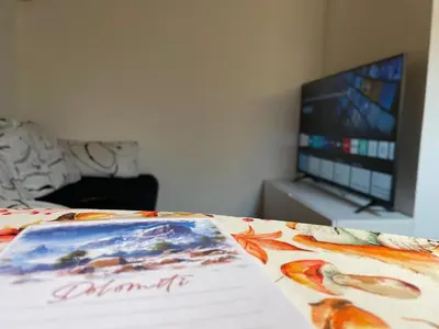 a bed with a comforter with a television in a room at Romantica Mansarda Alpina-Ski & Natura in Tesero