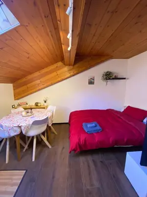 a bedroom with a red bed and a table at Romantica Mansarda Alpina-Ski & Natura in Tesero
