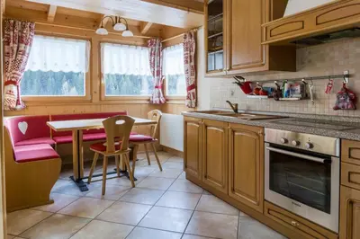 a small kitchen with a table and a red couch at Dolomites with Love in Mazzin