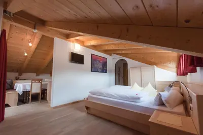 a bedroom with a bed in a room with wooden ceilings at Pension Garden Hotel in Colfosco