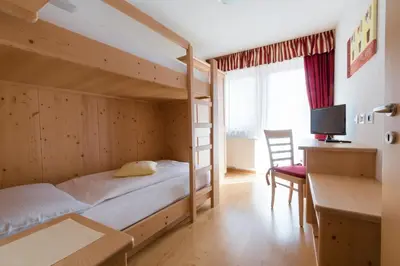 a bedroom with a bunk bed with a desk and a desk at Pension Garden Hotel in Colfosco