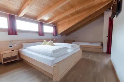 a bedroom with a large white bed in a room at Pension Garden Hotel in Colfosco