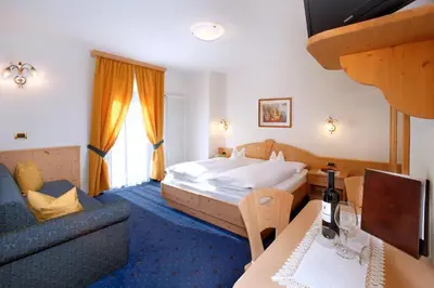 a hotel room with a bed and a couch at Hotel Else in Selva di Val Gardena