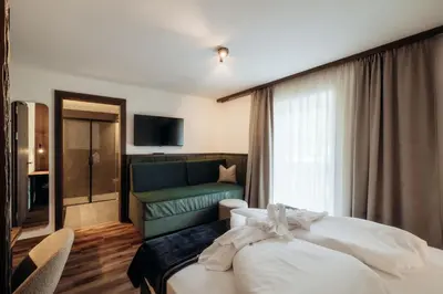 a hotel room with a bed and a couch at Hotel Else in Selva di Val Gardena