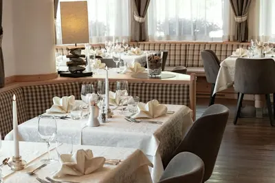 a dining room with tables with white tablecloths at Hotel Else in Selva di Val Gardena