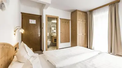 a bedroom with a bed and a bathroom at Hotel Else in Selva di Val Gardena
