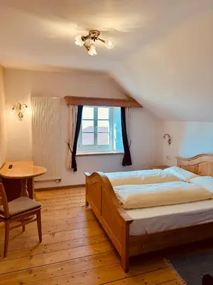 a bedroom with a bed and a table and a window at Oberraut in Brunico