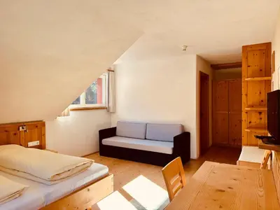 a bedroom with a bed and a couch in a room at Oberraut in Brunico
