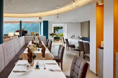a restaurant with white tables and chairs and windows at Hotel Paradies in Tirolo