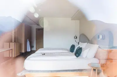 a bedroom with a white bed and a table at Hotel Paradies in Tirolo