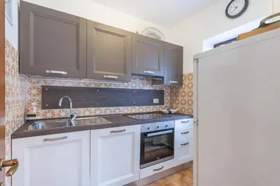 a kitchen with white cabinets and a sink at Condominio Val Biois in Falcade