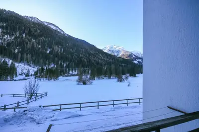 a snow covered field with a fence and mountains at Condominio Val Biois in Falcade