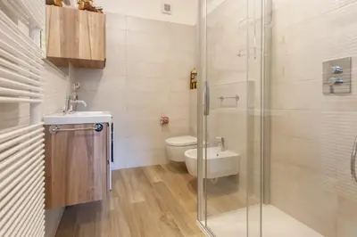 a bathroom with a toilet and a glass shower at Condominio Val Biois in Falcade