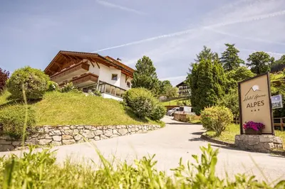 a sign in front of a house with a building at Hotel Garni Alpes in Schenna