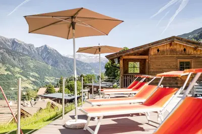 a group of lounge chairs and an umbrella at Hotel Garni Alpes in Schenna