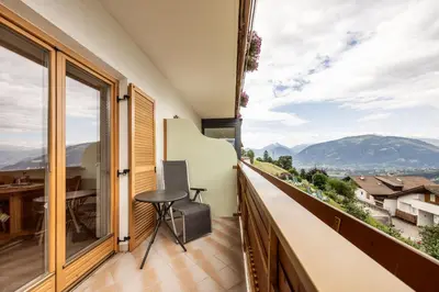 a balcony with a table and a view of mountains at Hotel Garni Alpes in Schenna