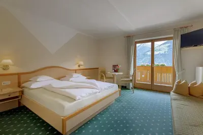 a hotel room with a bed and a large window at Hotel Garni Alpes in Schenna