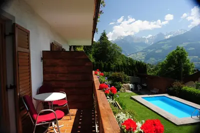 a patio with a table and chairs and a swimming pool at Haus Rosengarten in Tirolo