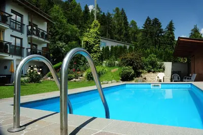 a swimming pool with metal hand rails next to a building at Haus Rosengarten in Tirolo