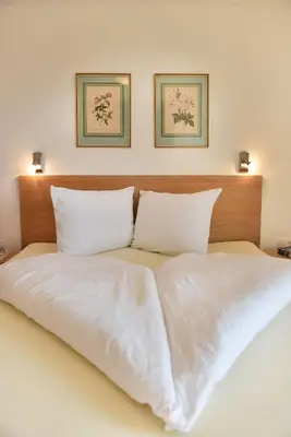 a white bed with two pillows and two pictures on the wall at Haus Rosengarten in Tirolo