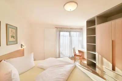a bedroom with a bed and a chair and a window at Haus Rosengarten in Tirolo